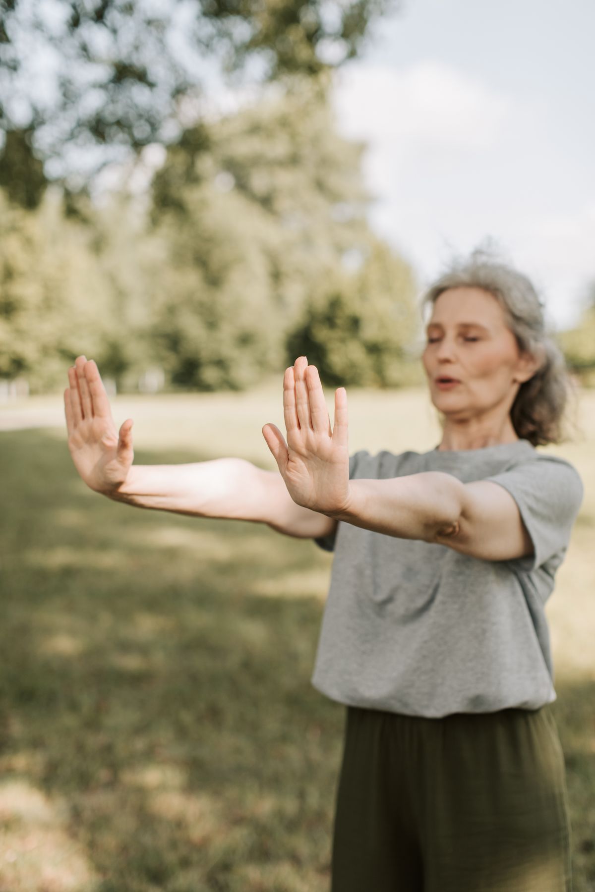 Elderly man practicing Baduanjin qigong in a park at dawn