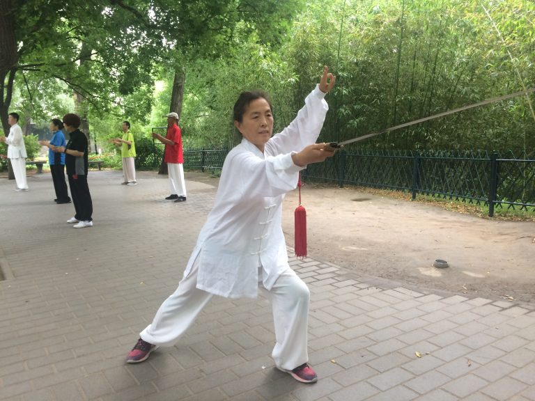 练习者做云剑动作,剑尖在头顶一侧画圆的特写